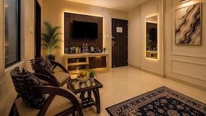 A modern living room with a flat-screen TV, wooden furniture, a coffee table, and a decorative rug. - Hotel Smart International (New Delhi)
