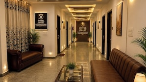A hotel lobby with a central reception desk, sofas, potted plants, and a polished floor. - Hotel Smart International (New Delhi)