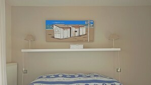 Una camera da letto con un letto, una mensola a parete e un quadro raffigurante una casa.