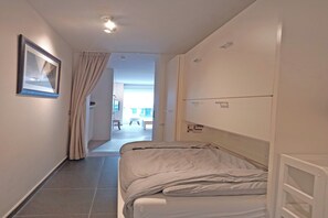 A hotel room with a bed, a window with curtains, a picture on the wall, and a view of the outside. - Coastal Family Escape in Knokke (KNOKKE - HEIST)
