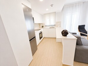 A modern kitchen with white cabinetry, a built-in oven, and a refrigerator. - Apartamento la Bodega con piscina (Conil de la Frontera)