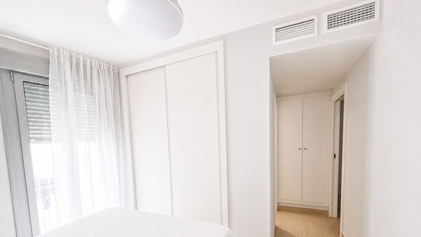 Ein Schlafzimmer mit einem Bett, einer Tür und einem Flur, der in einen weiteren Raum führt.
