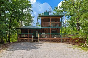 A two-story cabin with a porch and a gravel driveway. - Hot Tub + Wraparound Decks + Arcade | Layered Ridge Views | Dream Chaser (Sevierville)