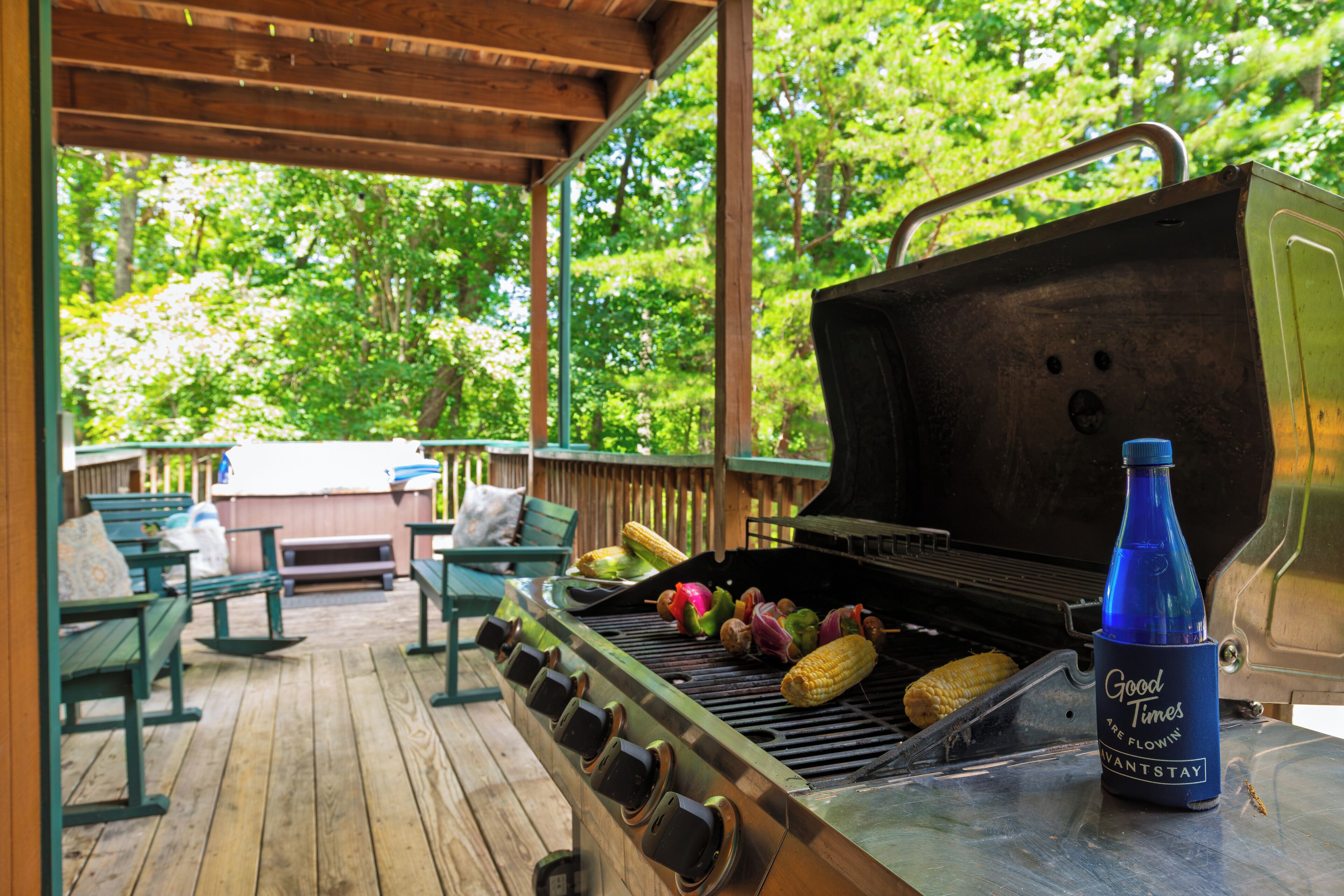 Una parrilla al aire libre con verduras y una botella en una terraza de madera.