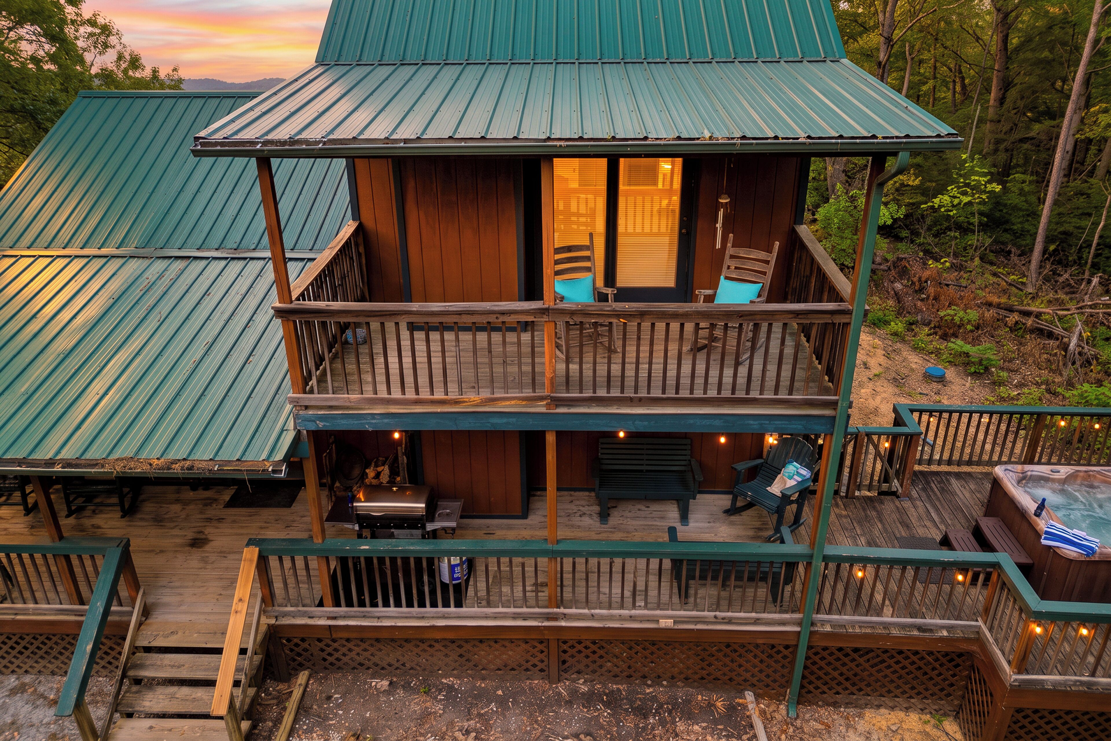 A two-story cabin with a balcony, a hot tub, and a deck area.