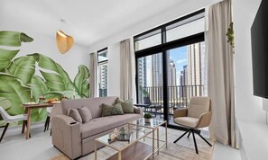 A modern living room with a sofa, armchair, coffee table, and large windows offering a city view. - Blossom & Palm 1BR | designer Creek Harbour home (Dubai)