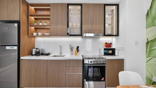 Eine moderne Küche mit Holzschränken, einem Einbauofen, einem Kühlschrank und einer Mikrowelle.