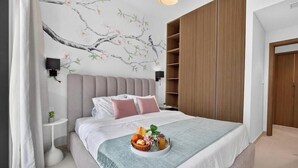 Ein Schlafzimmer mit Bett, Nachttischen, einem an der Wand befestigten Fernseher, einem Holzschrank und einem dekorativen Wandbild.