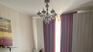 Habitación de hotel con dos camas, una araña, un cuadro, un microondas y un armario.