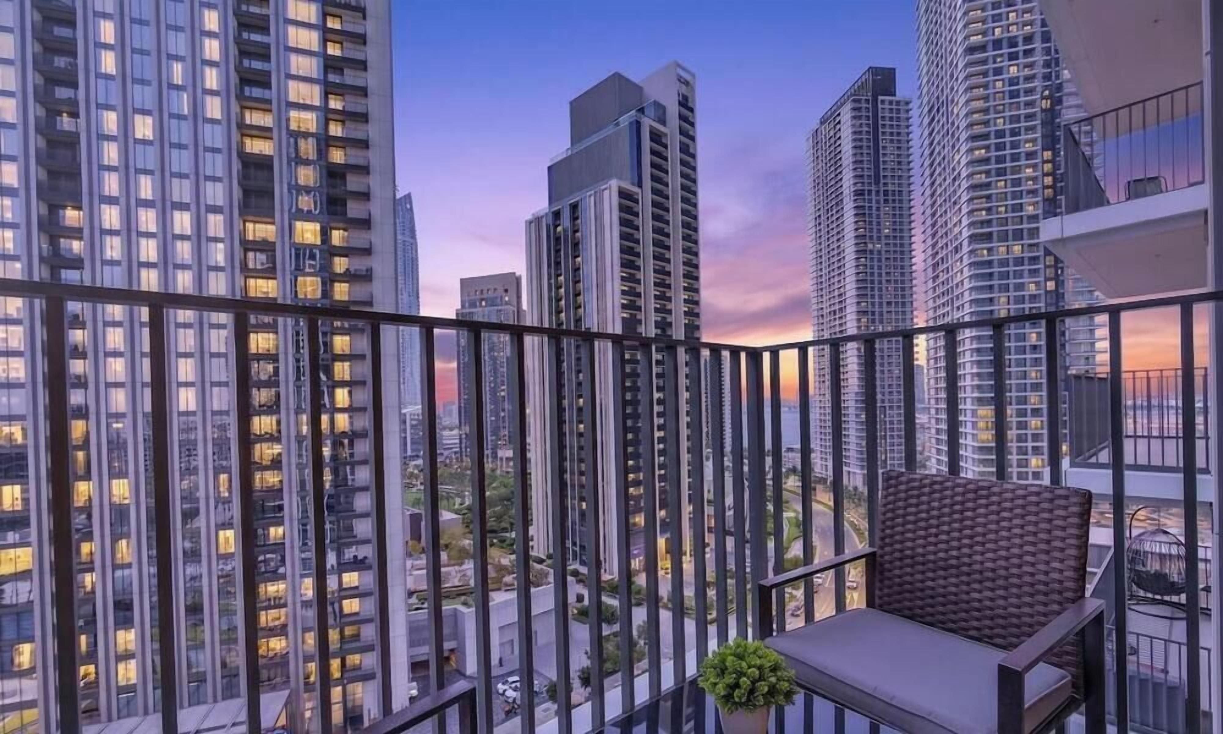 A balcony with a view of high-rise buildings, a chair, and a small plant.