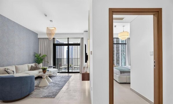 Ein modernes Wohnzimmer mit einer Couch, einem Couchtisch und Blick auf die Stadt durch große Fenster.