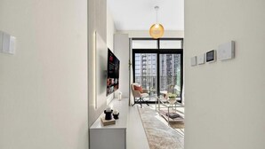 En moderne stue med sofa, sofabord og et stort vindue med udsigt over byen.