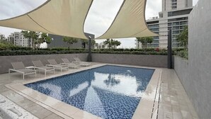 En swimmingpool med liggestole og et parasol.