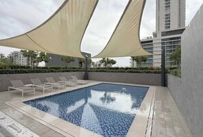 Ein Schwimmbecken mit Liegestühlen und Sonnensegel.