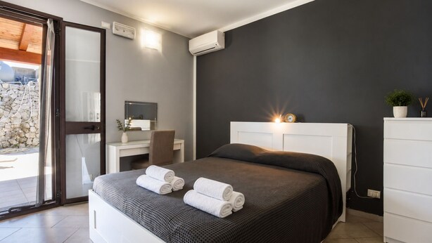 A modern bedroom with a bed, bedside table, and a desk with a chair. - Villa in Brucoli with 5 bedrooms sleeps 13 (Brucoli)