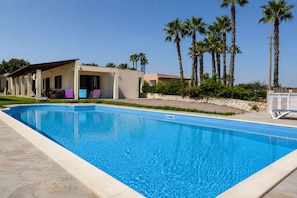 A swimming pool with a clear blue water surface, surrounded by a paved deck. - Villa in Brucoli with 5 bedrooms sleeps 13 (Brucoli)