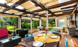 An outdoor patio with a table set for dining, surrounded by wicker furniture and chairs. - Vacation Home in Arenella with 4 bedrooms sleeps 11 (Arenella)