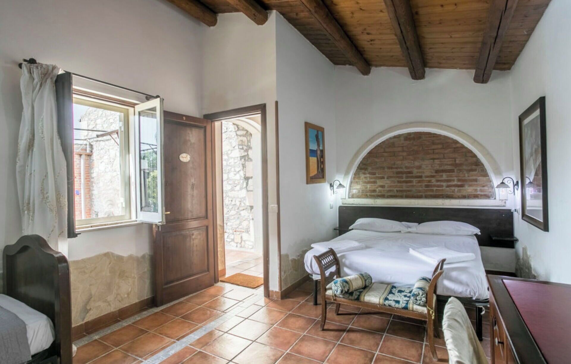 Un dormitorio con cama, una silla, una puerta de madera y una ventana.