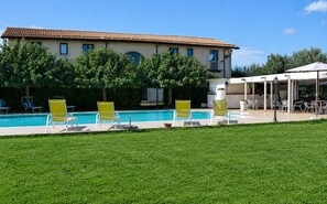 A pool area with lounge chairs, a building with a tiled roof, and a covered outdoor seating area. - Vacation Home in Arenella with 4 bedrooms sleeps 11 (Arenella)