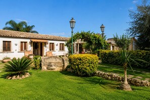A traditional white building with a tiled roof, stone pathway, and well-maintained garden with various plants and a stone wall. - Vacation Home in Arenella with 4 bedrooms sleeps 11 (Arenella)