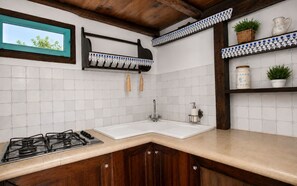 A kitchen with a gas stove, white tiled backsplash, wooden cabinets, a sink, and a window with a view of trees. - Vacation Home in Arenella with 4 bedrooms sleeps 11 (Arenella)