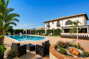 A swimming pool with lounge chairs, a pergola, and a large house with a balcony. - Vacation Home in Arenella with 4 bedrooms sleeps 11 (Arenella)