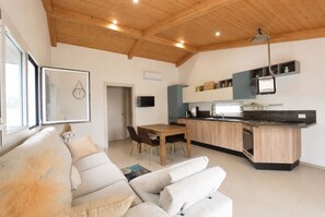 Eine moderne Küche mit Holzausstattung, ein Essbereich mit Tisch und Stühlen sowie ein Wohnzimmer mit Sofa und Kamin.