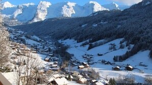 A snow-covered village with houses and mountains in the background. - La Favellaz: Exceptional panoramic view of the Aravis mountain range and the village (Le Grand-Bornand)