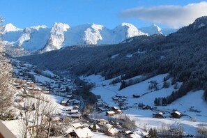 A snow-covered village with houses and mountains in the background. - La Favellaz: Exceptional panoramic view of the Aravis mountain range and the village (Le Grand-Bornand)