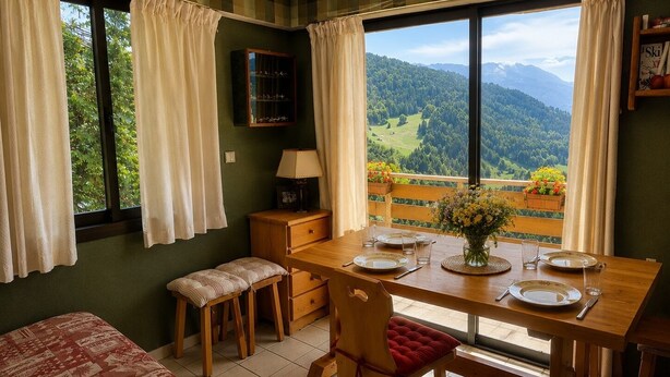 A dining area with a table set for two, a bench, and a view of a mountainous landscape. - La Favellaz: Exceptional panoramic view of the Aravis mountain range and the village (Le Grand-Bornand)
