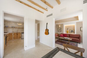 Un vaste espace de vie comprenant un canapé rouge, une guitare et une table basse.