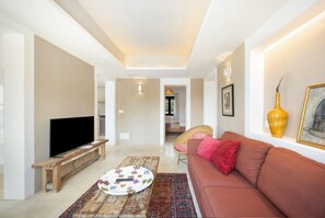 Una sala de estar con televisión, sofá, una mesa de centro y alfombra estampada.