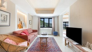 A living room with a sofa, a coffee table, a TV, and a large window.