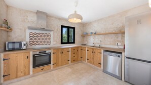 Uma cozinha moderna com armários de madeira, forno embutido, micro-ondas e máquina de lavar louça.