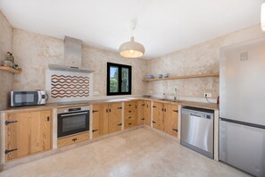 Eine moderne Küche mit Holzausstattung, Backofen, Mikrowelle und Geschirrspüler.
