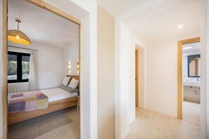 Un dormitorio con cama, ventana con cortinas, lámpara de noche y vistas al exterior.