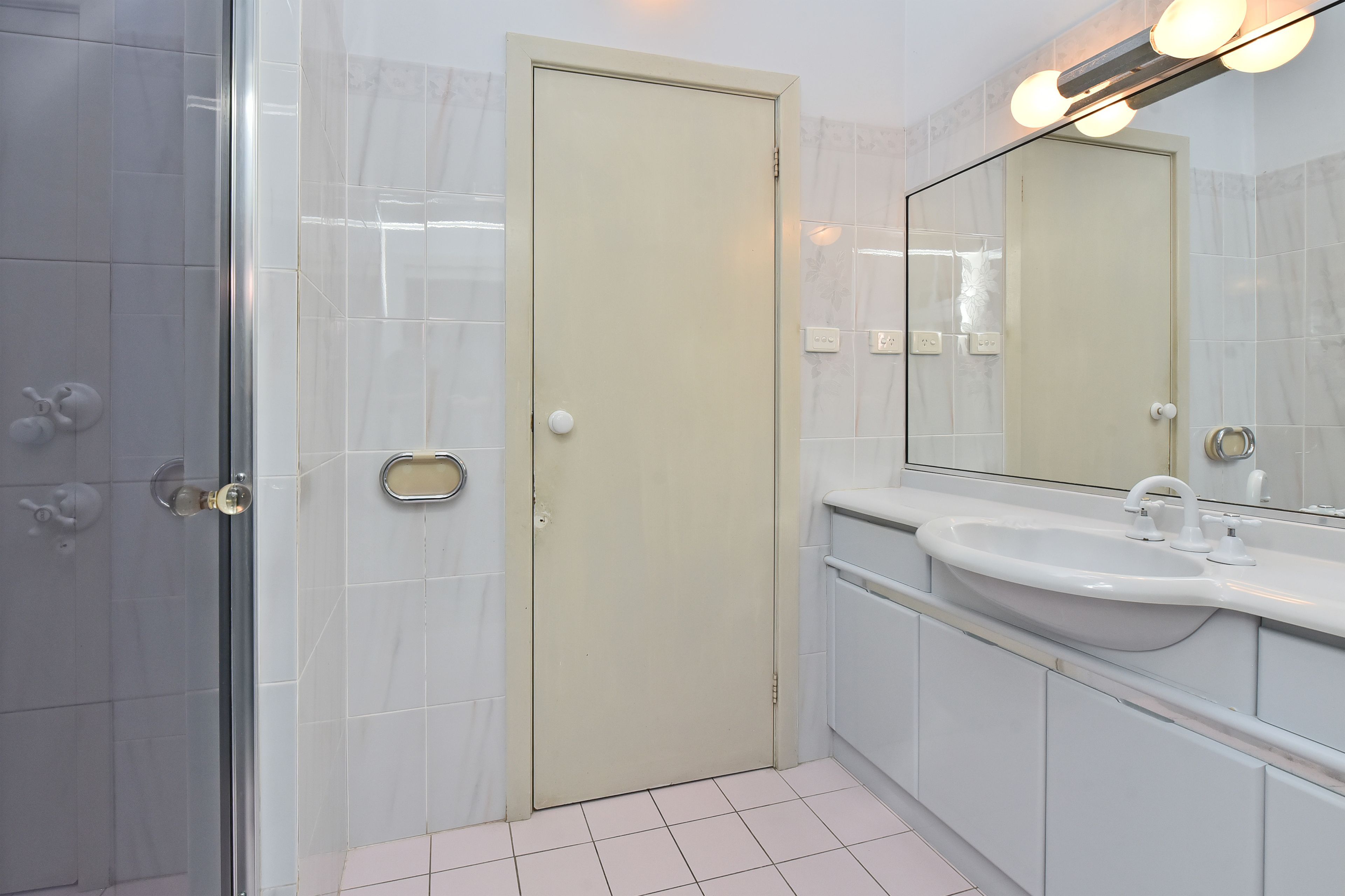 Une salle de bain avec une douche, un lavabo et un miroir.