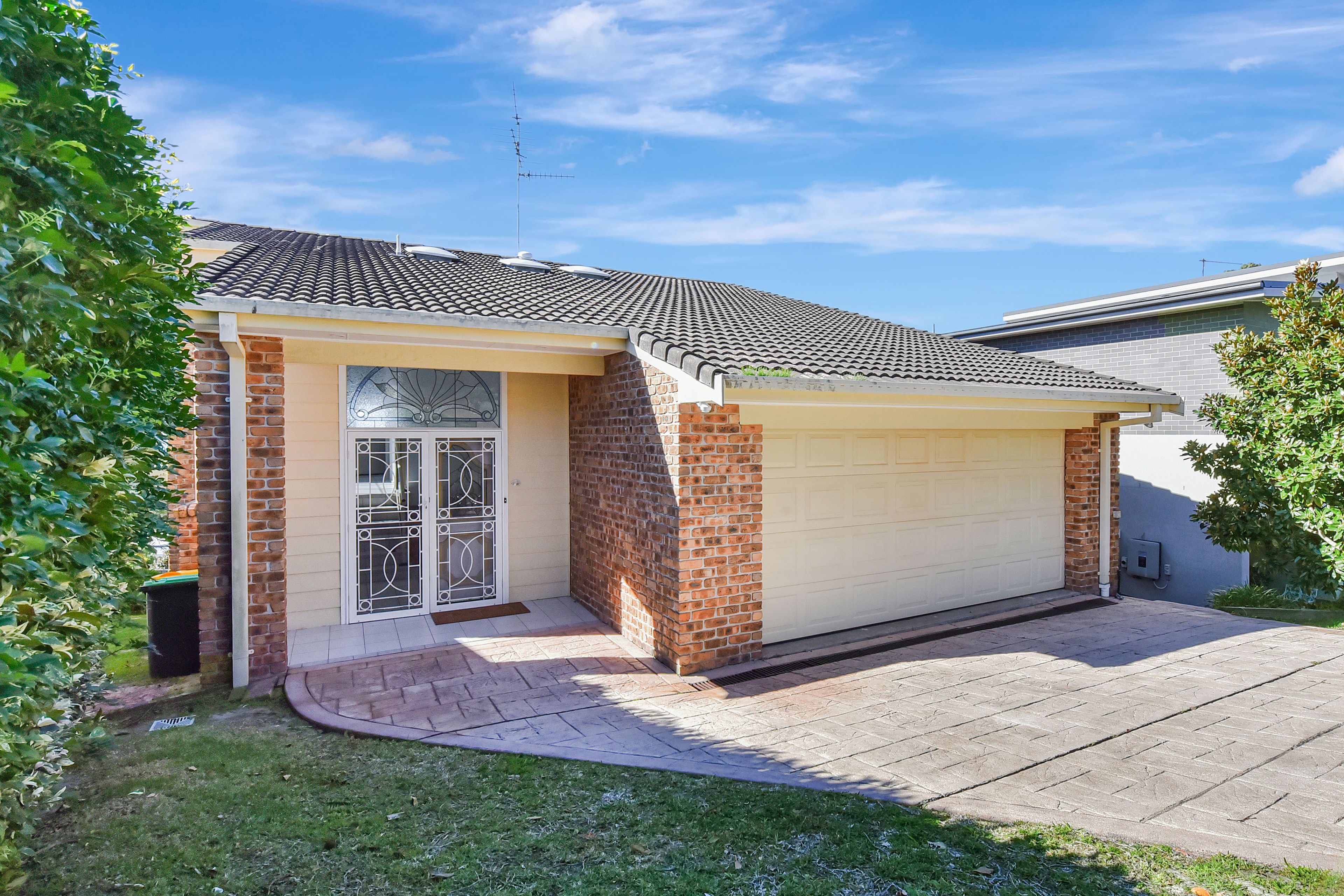 A residential house with a garage, a brick facade, and a tiled roof.