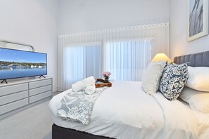 A modern hotel room with a large bed, a flat-screen TV, and a view of the sea. - Bella-Vista On Canomii (Nelson Bay)