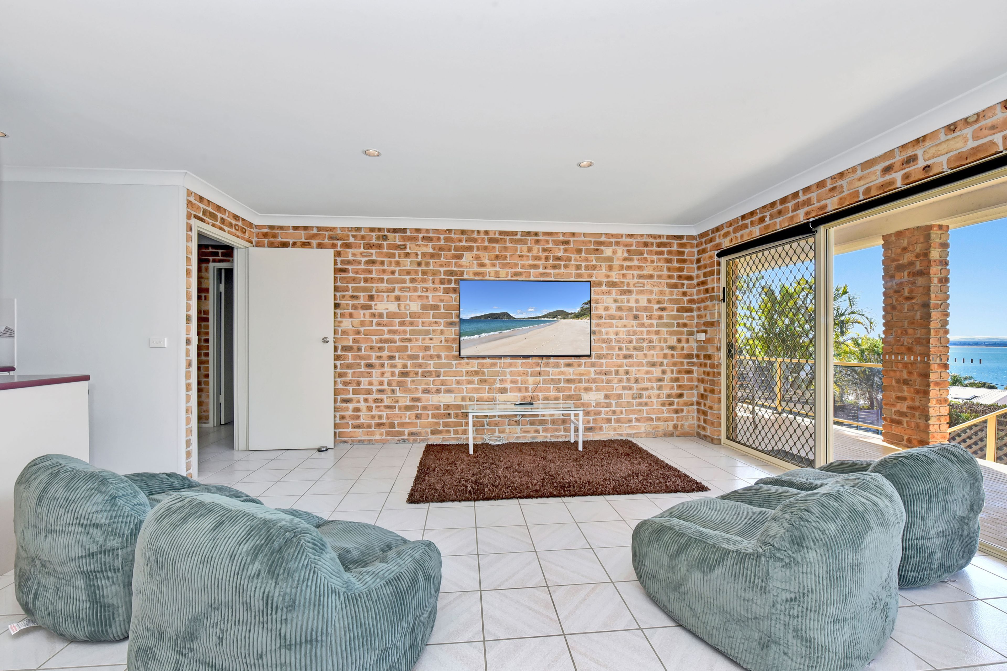 Un salon moderne avec un mur en briques, un téléviseur à écran plat et une vue sur la mer.