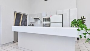 Eine moderne Küche mit weißen Schränken, einem eingebauten Backofen und einer Mikrowelle.