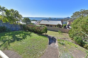 A residential area with a grassy yard, a paved pathway, and houses with varying roof styles. - Bella-Vista On Canomii (Nelson Bay)