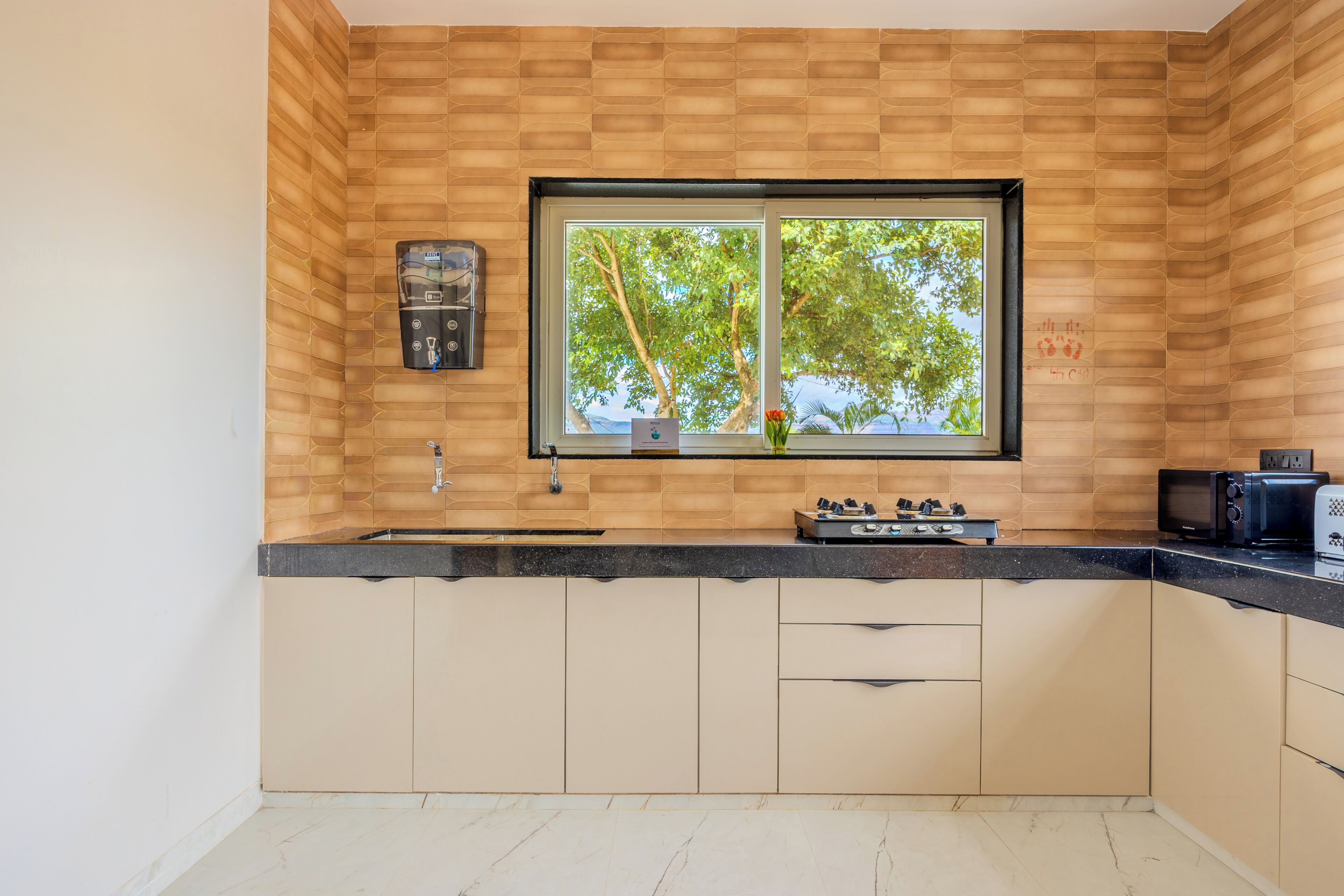 Une cuisine équipée d’une fenêtre, d’un distributeur d’eau, d’une cuisinière et d’un four à micro-ondes.