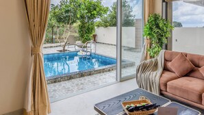 Ein modernes Wohnzimmer mit Blick auf einen Pool, inklusive Sofa, Couchtisch und Deckenventilator.