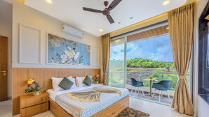 Ein Schlafzimmer mit einem großen Bett, einem Deckenventilator, einem Gemälde und Blick auf eine Landschaft durch eine Schiebetür.