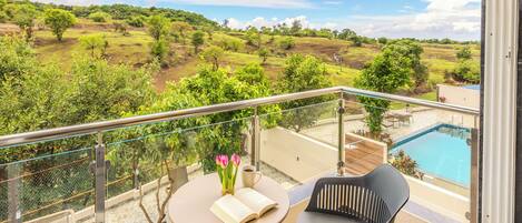 Un balcón con vista a una piscina y el paisaje.