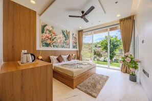 A modern bedroom with a large bed, a ceiling fan, and a view of a garden through large windows. - ELIVAAS SK Villa 4BHK Hideaway with Pool (Lonavala)