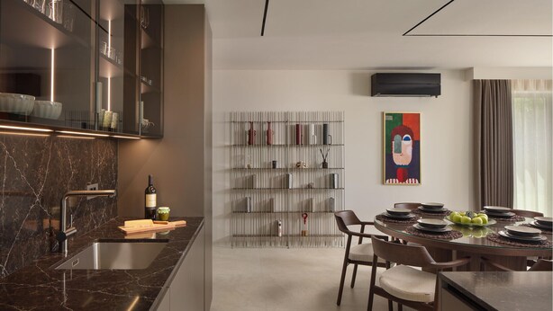 Een moderne keuken met een marmeren aanrechtblad, een eethoek met een glazen tafel en een wandairconditioner.