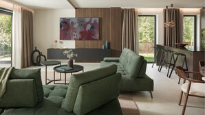 Een moderne woonkamer met een groene bank, een salontafel en een schilderij aan de muur.