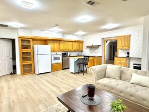 Une cuisine moderne avec des meubles en bois, un réfrigérateur et un coin repas comprenant un canapé et une table basse.